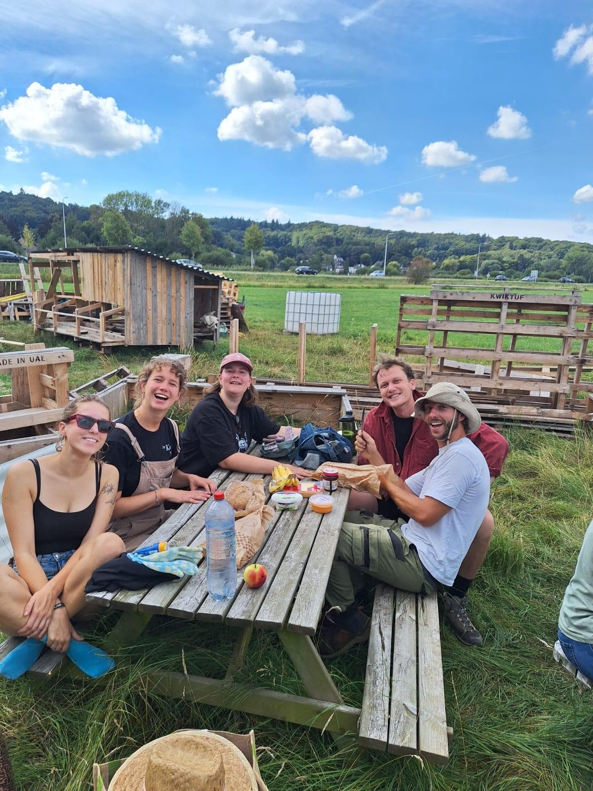 Vrijwilligers samen aan tafel na een werkdag op Pluktuin Meraki